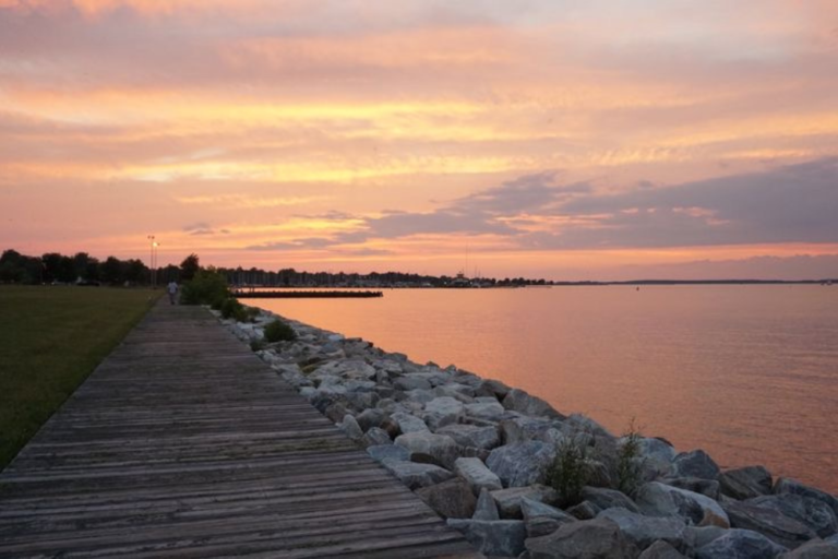 Orange, yellow, and purple sunset over a bay with a boardwalk