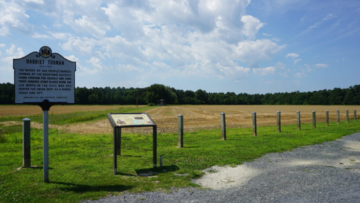 View of empty farmland and a sign noting a Harriet Tubman Underground Railroad site