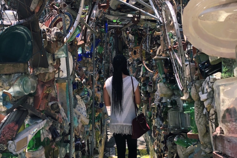 Woman walking through an art installment of glass bottles, ceramic, and found items