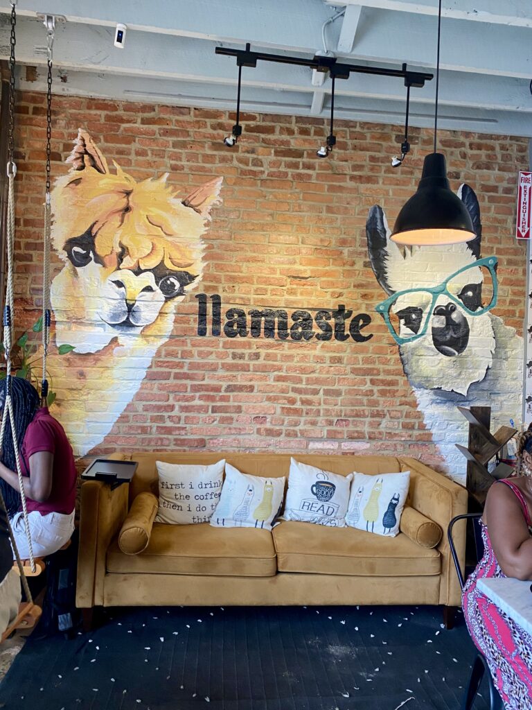 Brick wall with two llamas painted on it and a couch in front of it