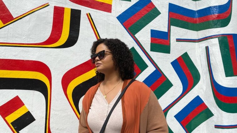 Woman in front of a wall mural of different striped flags