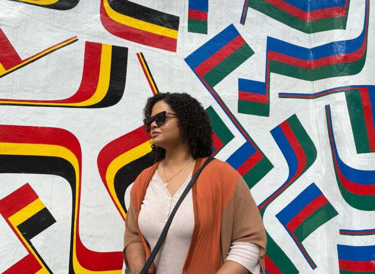 Woman in front of a wall mural of different striped flags