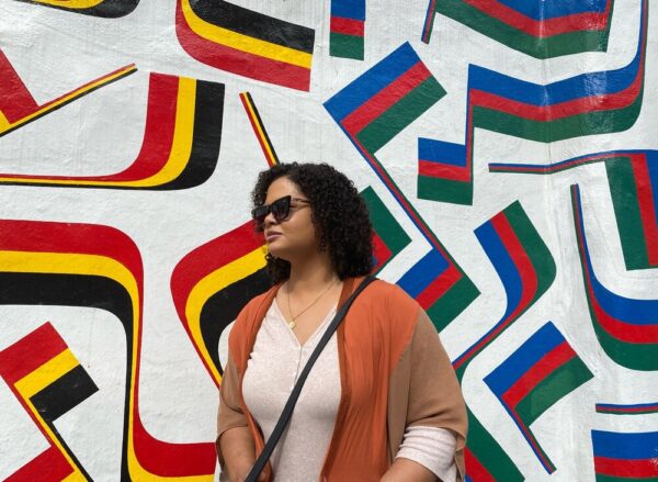 Woman in front of a wall mural of different striped flags