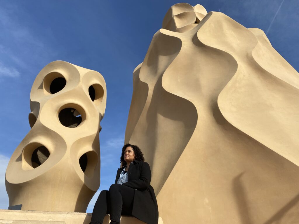 Woman sitting in front of two tall sculptures in Barcelona Spain