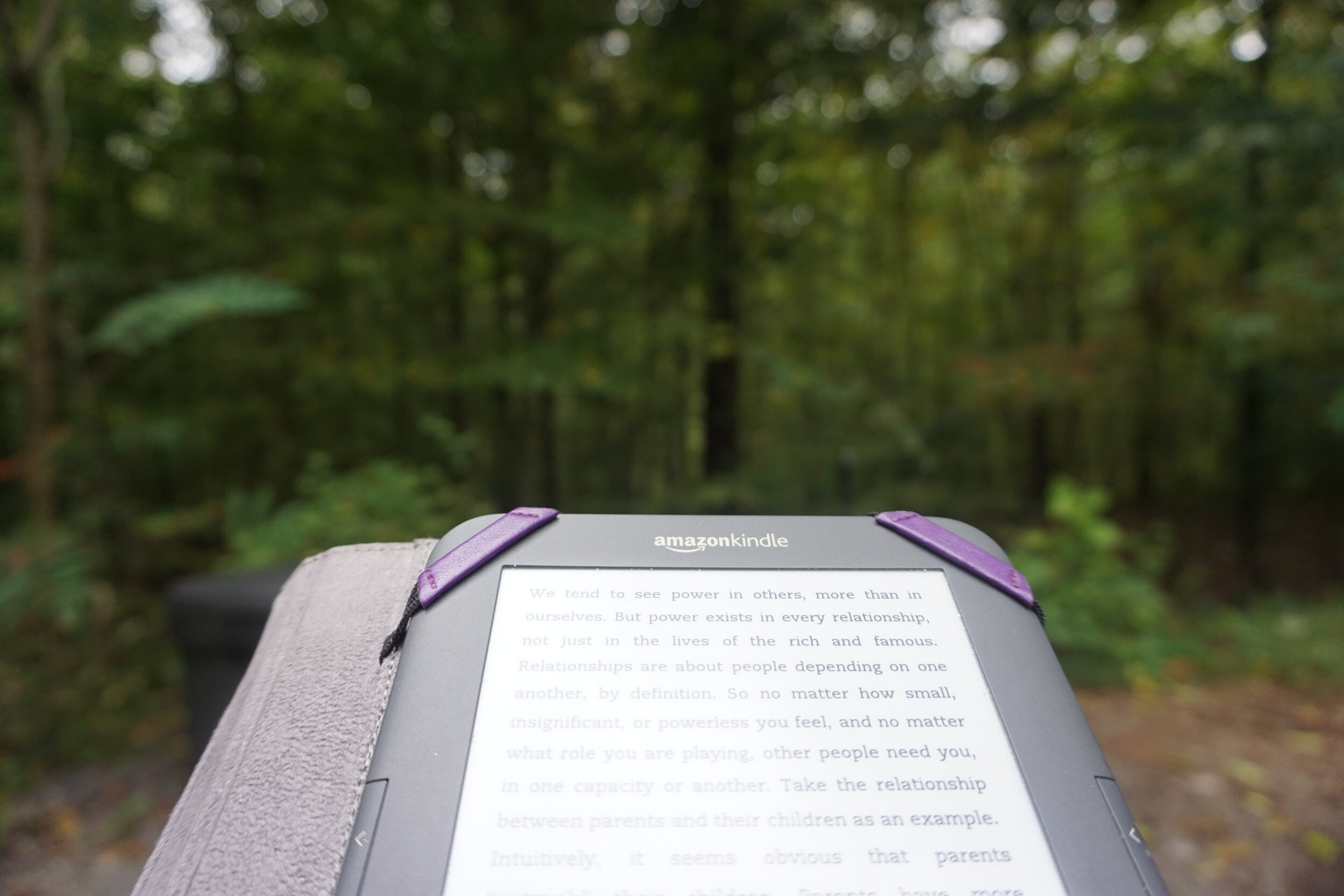 An Amazon Kindle and the woods in the background