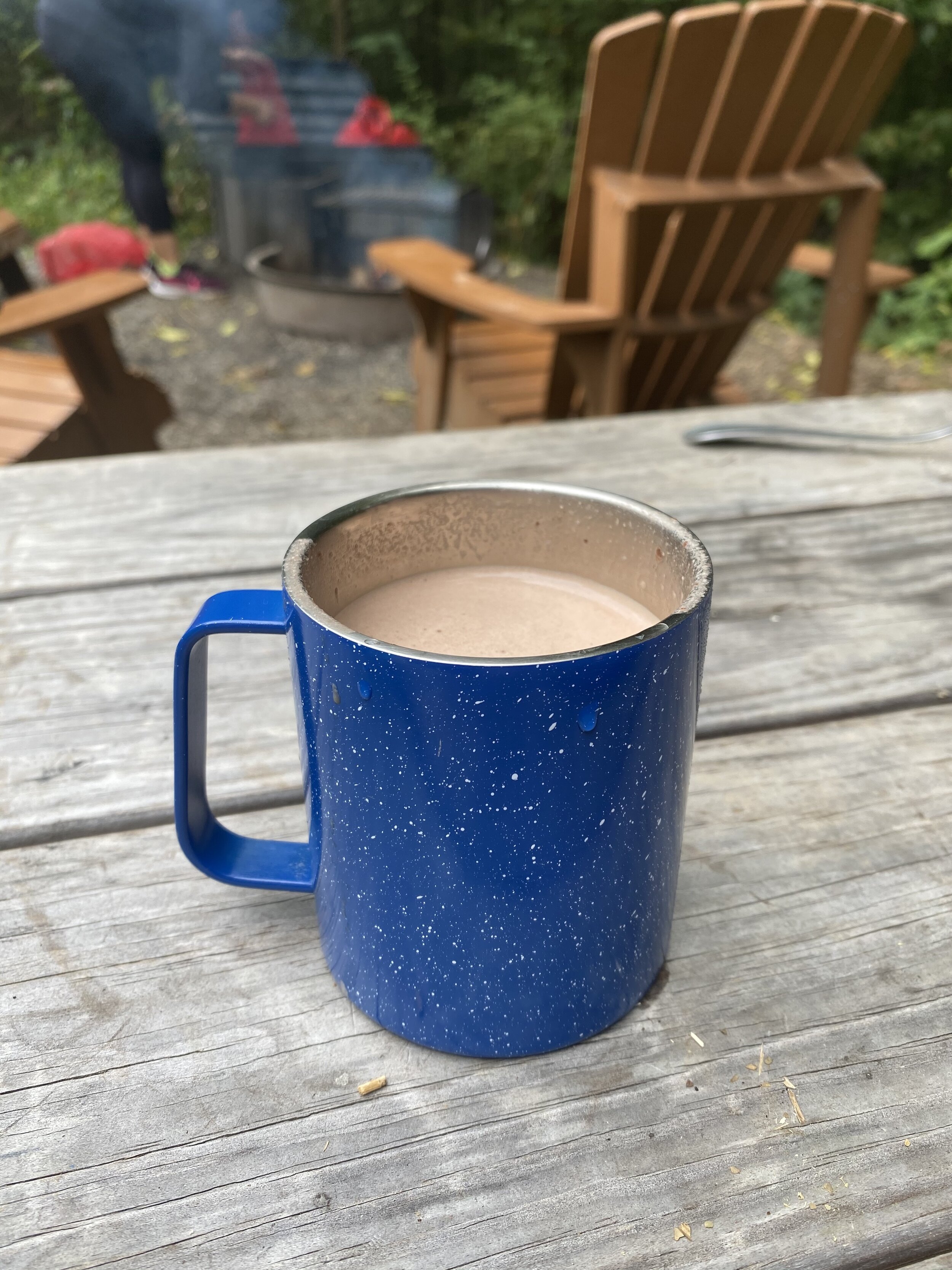 Cup of hot chocolate on a picnic table in the woods