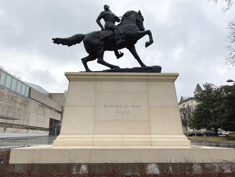 Tall sculpture of a black man on a horse atop a white marble pedestal