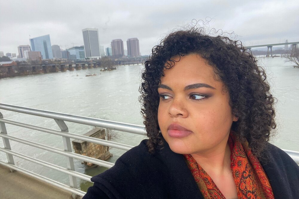 Selfie of woman on the Belle Isle pedestrian bridge in Richmond, Virginia with the skyline in the background