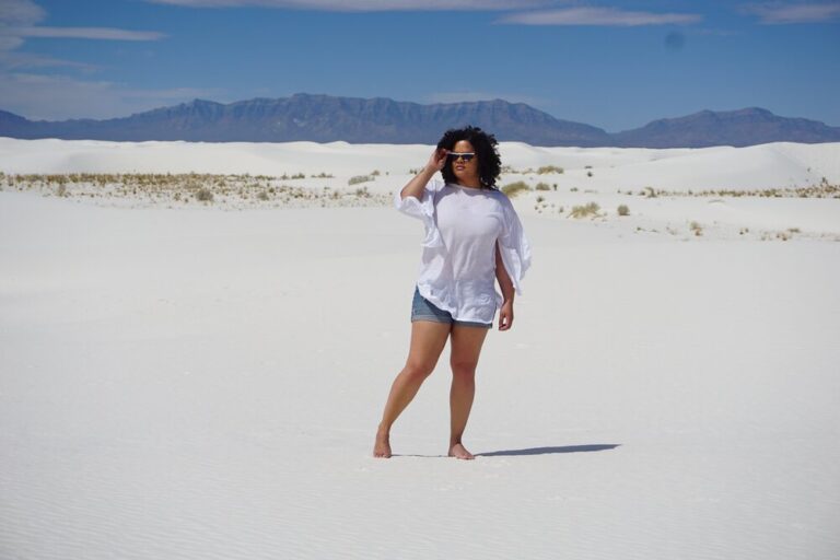 Woman standing on a white sand dune with mountains in the background