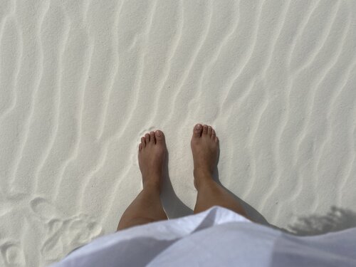 Woman's feet standing on white gypsum sand dune in New Mexico