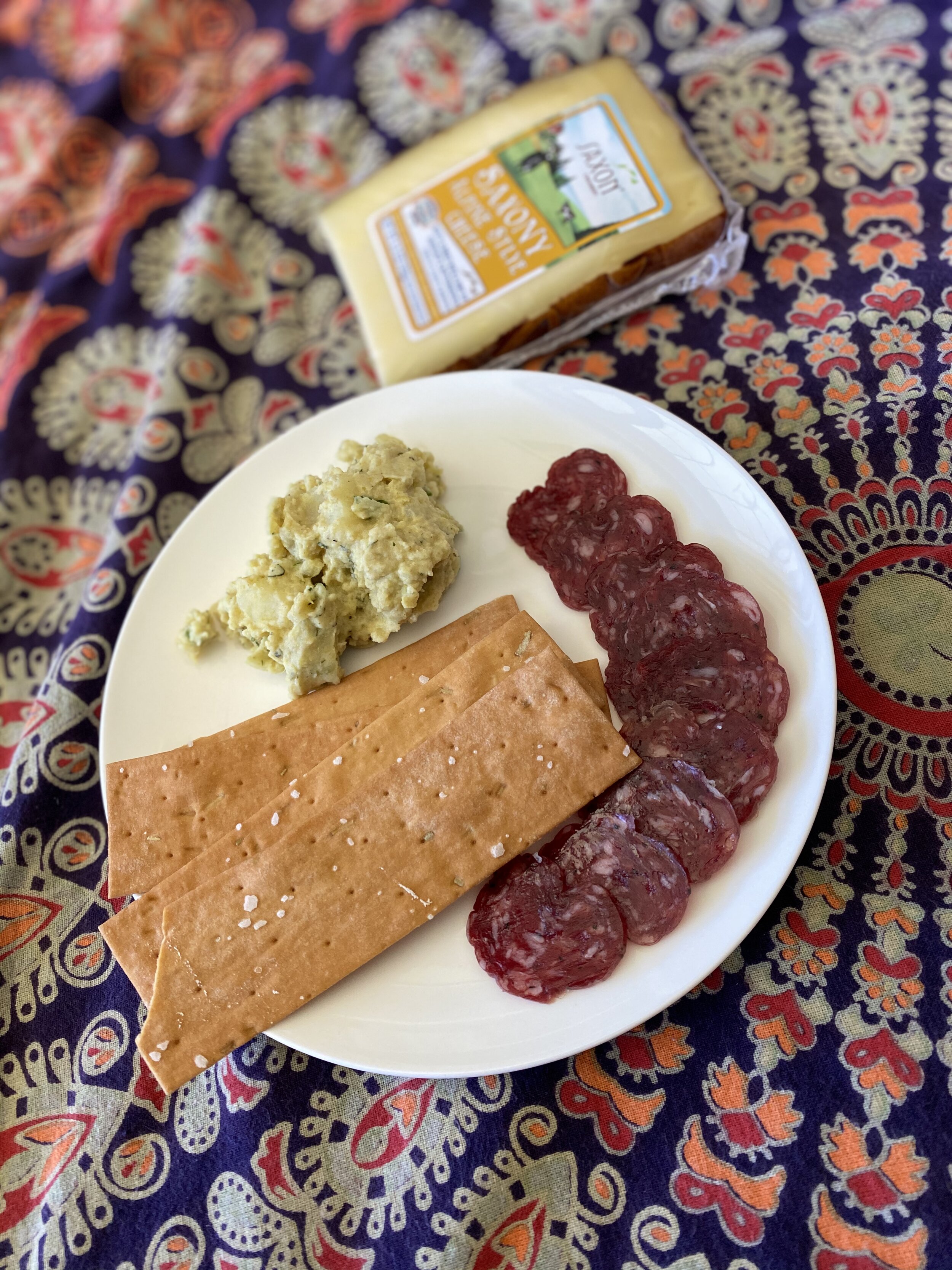 Plate of meat, cheese, and crackers on a picnic blanket for an AmazingCo mystery picnic