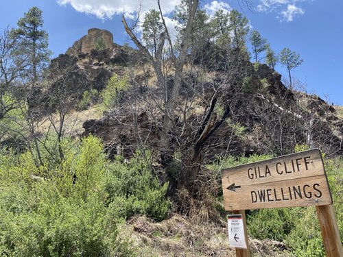 Sign pointing towards cliff dwellings with New Mexico mountains in the background