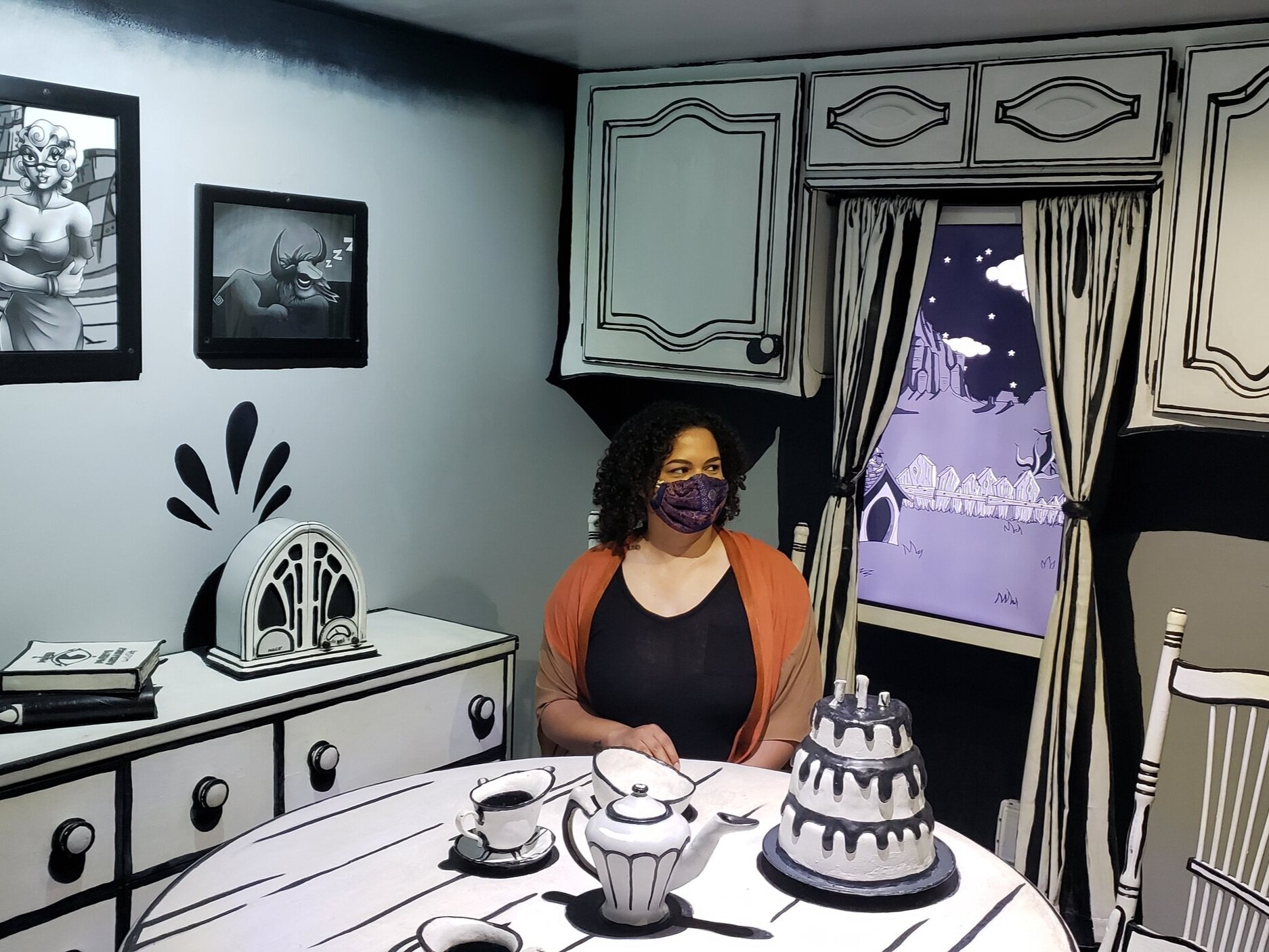 Woman sitting at the kitchen table in an art exhibit designed in all black and white