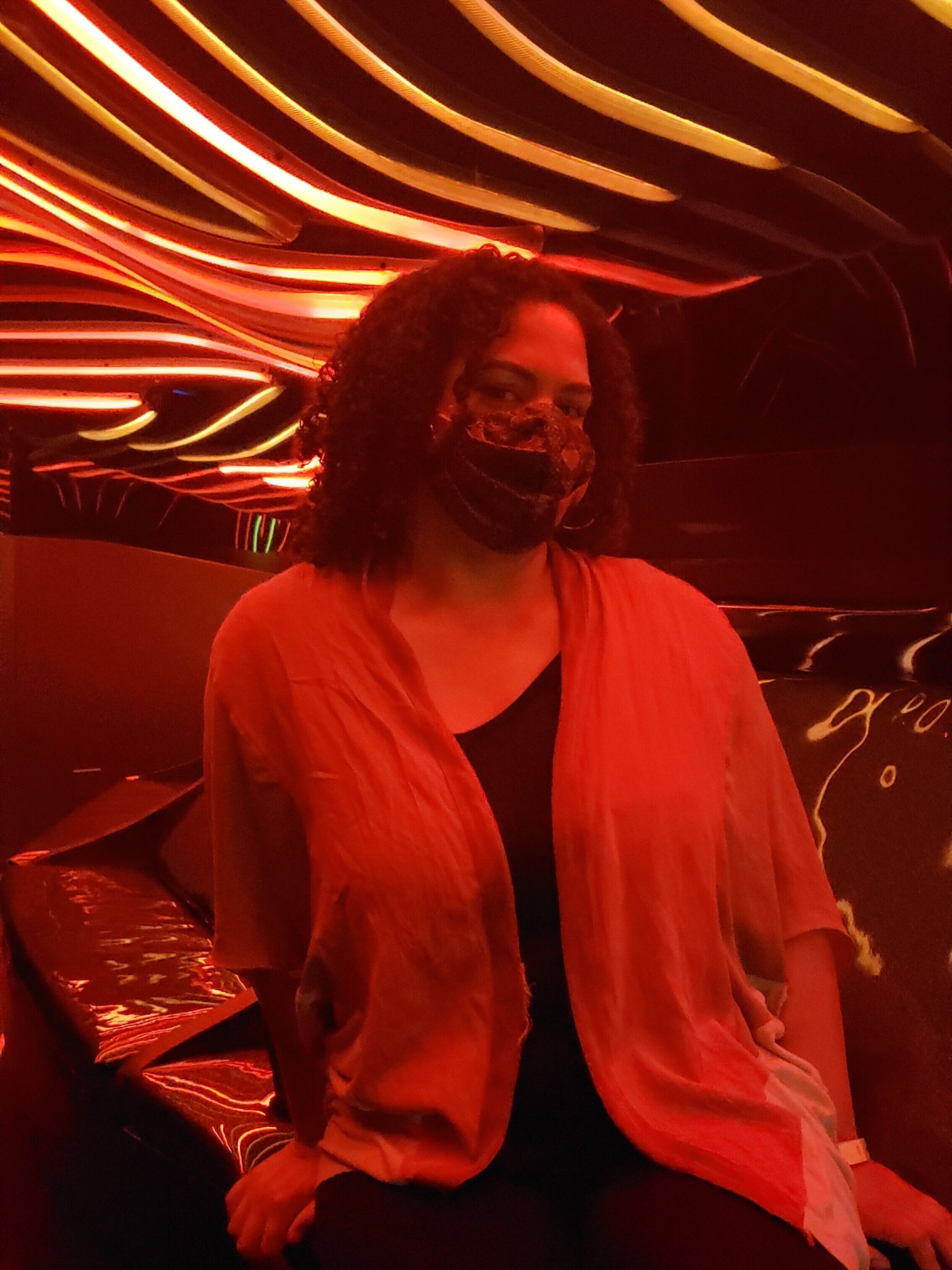 Woman sitting on a couch under red neon lights in an interactive art exhibit