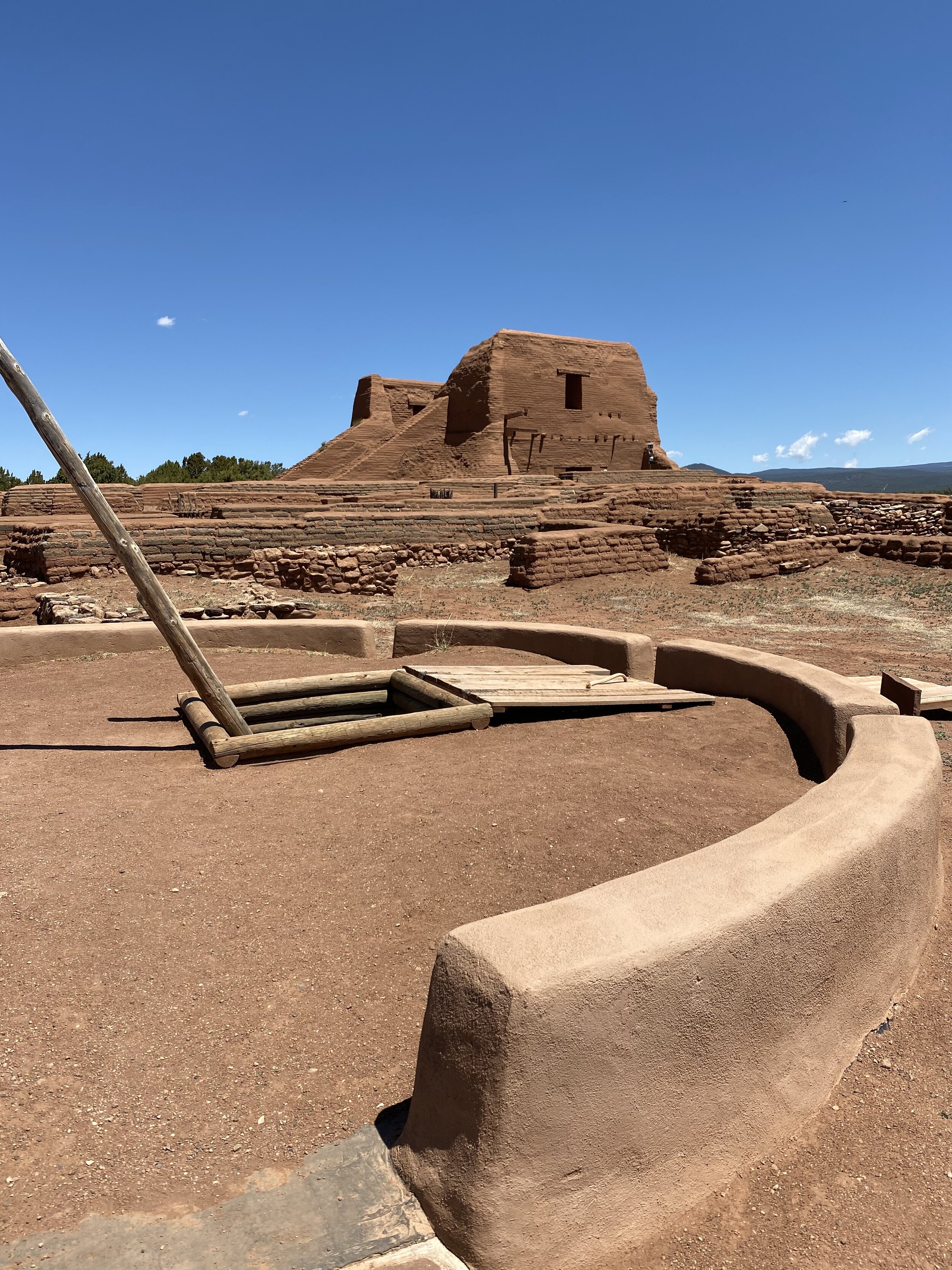 Kiva with view of the mission church in the background at Pecos National Historical Park