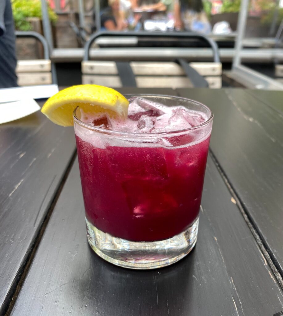 A red cocktail with a lemon slice on a table
