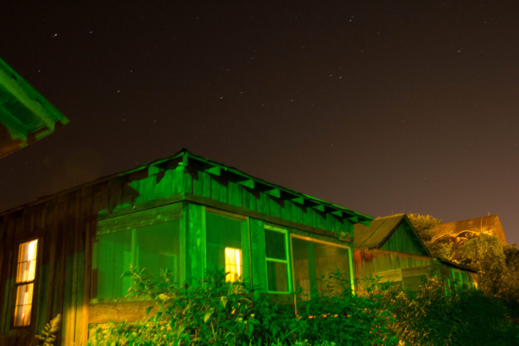 Wooden cabin lit up by green lights at night