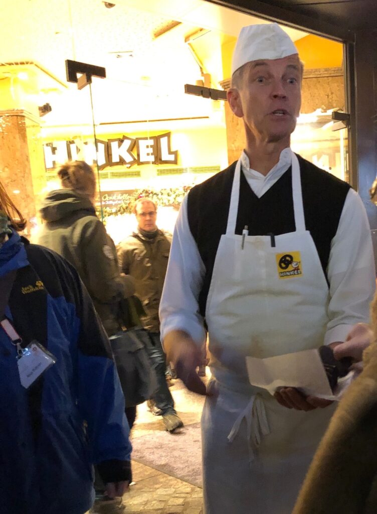Man in a baker's apron handing out German gingerbread cookies in front of an historic bakery in Dusseldorf, Germany