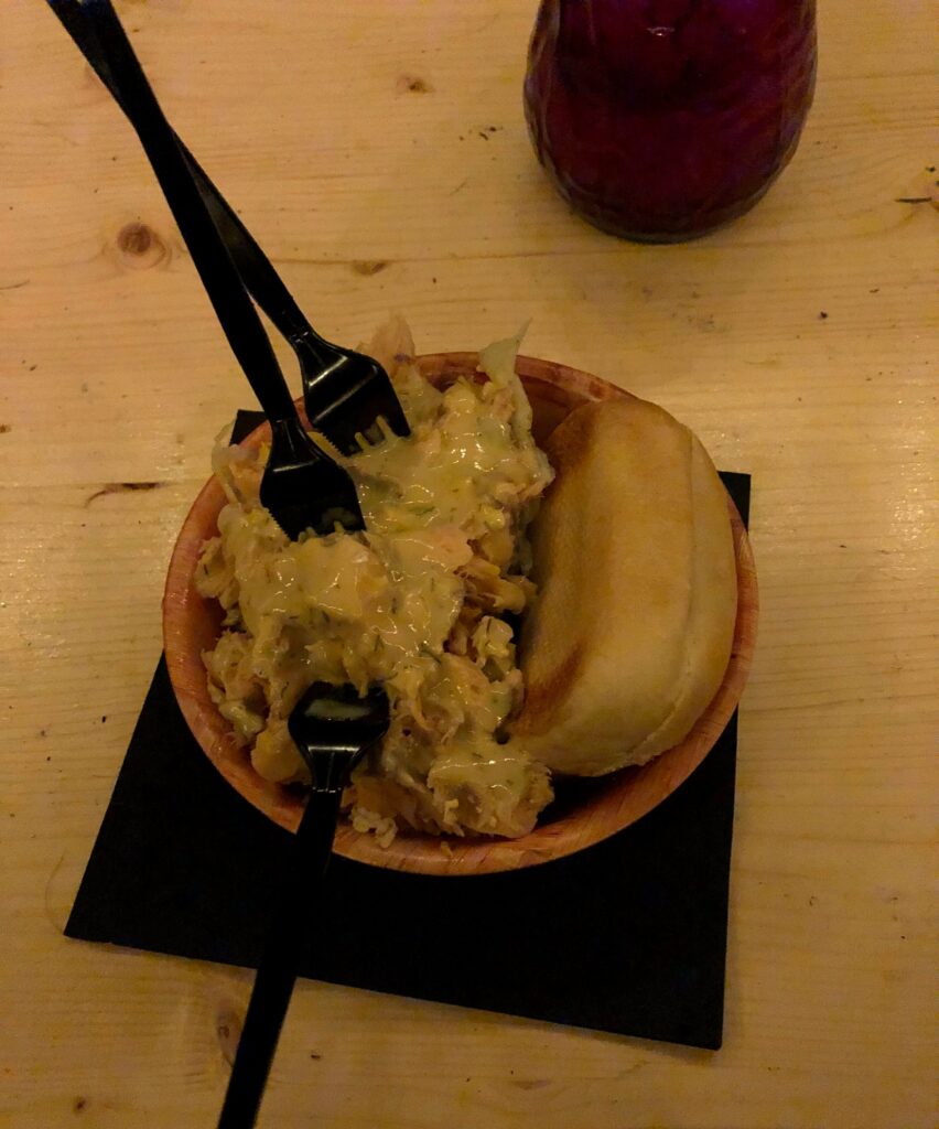 Bowl of flamed salmon with a bread roll at a German Christmas market