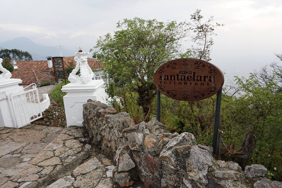 Sign for a restaurant along a stone path with white restaurant behind it