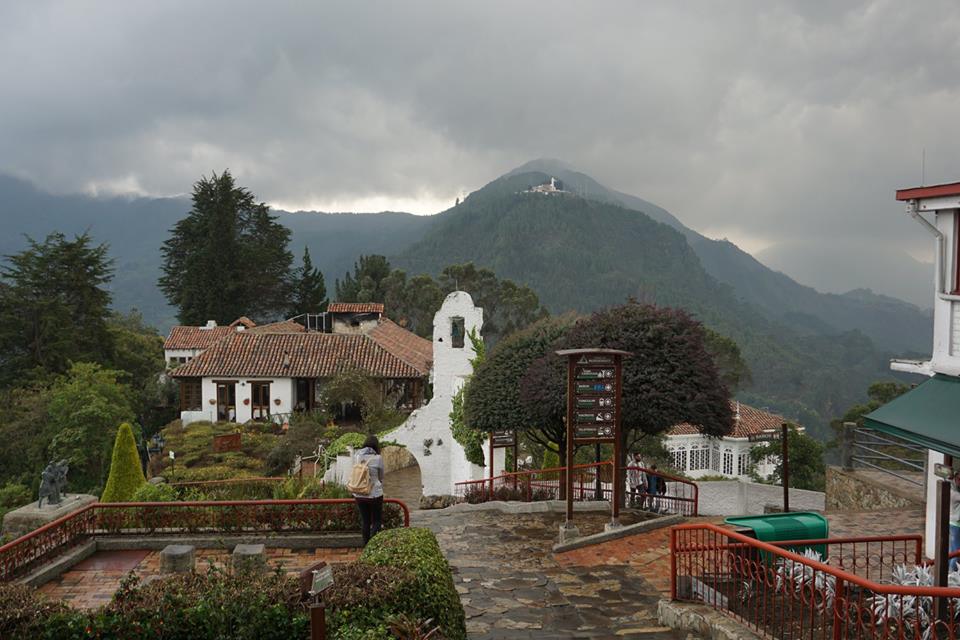 Buildings atop Montserrate mountain in Bogotá Colombia and mountain range in the background with gray clouds