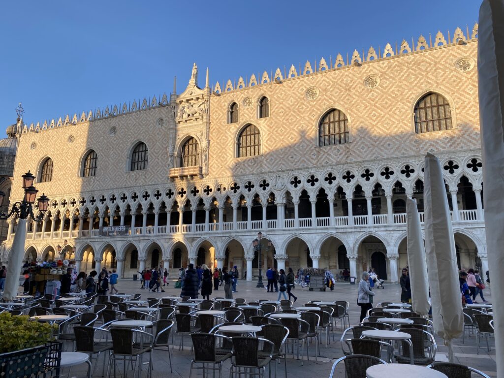 Doge's Palace with restaurant seats in front of it in a plaza