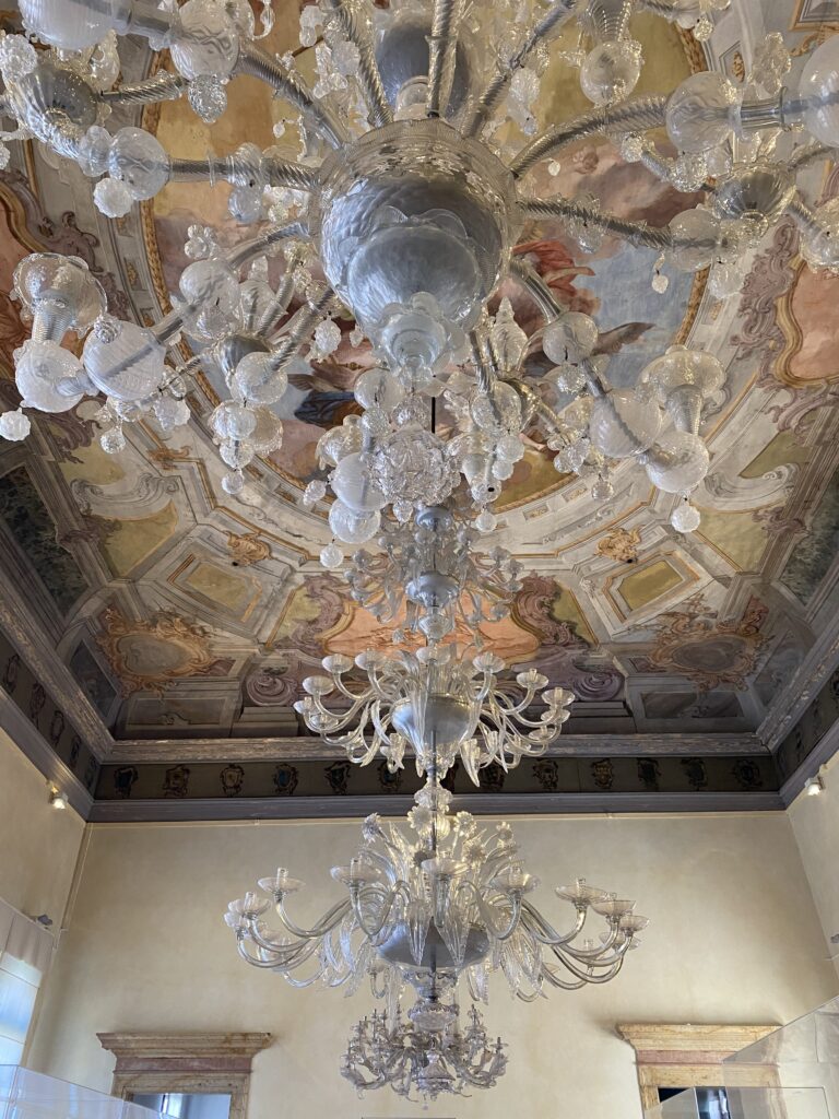 Glass chandeliers hanging from a frescoe ceiling in Murano Italy
