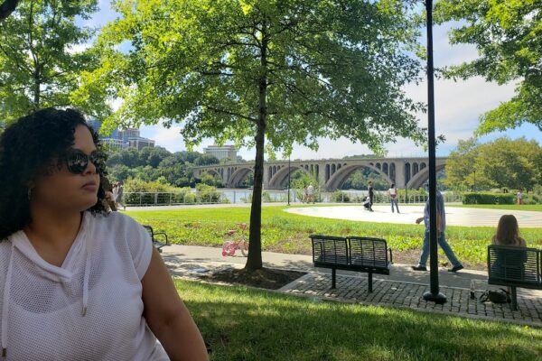 Woman in forefront with Georgetown, Washington DC bridge, river, and park in the background
