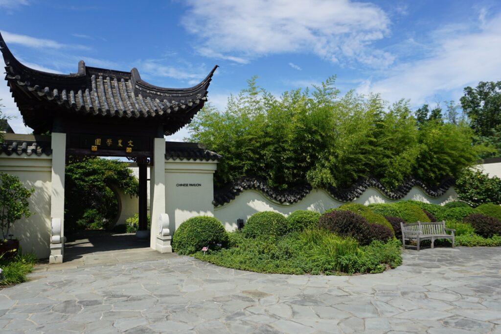 Chinese-style garden entrance lined with trees and bushes