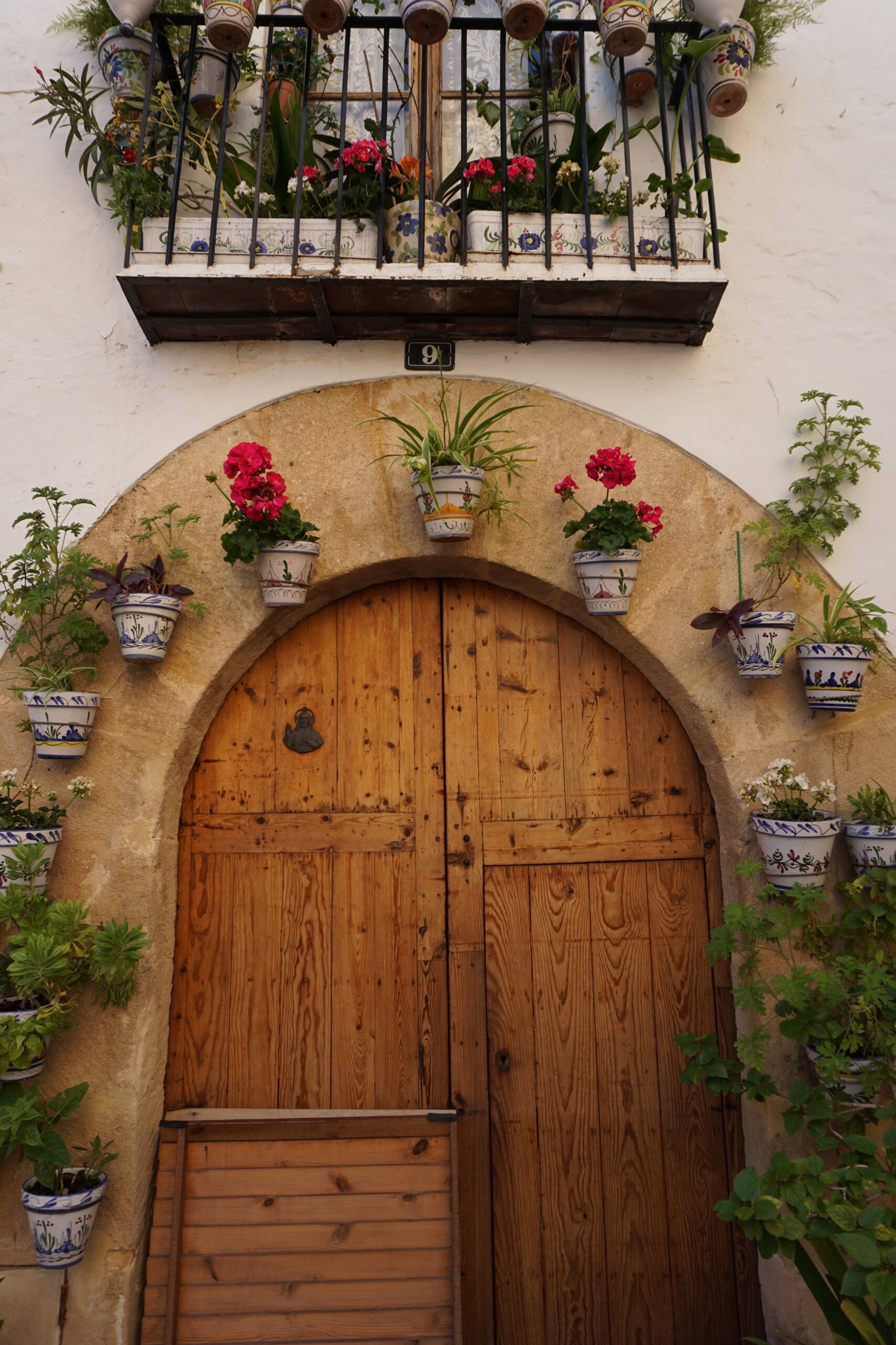 Rounded wooden door lined with flowers in Javea Spain
