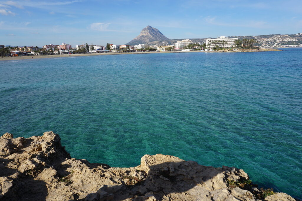 View of turquoise Mediterranean Sea water with town and a mountain in the background