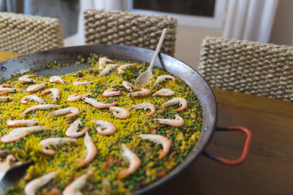Pan of Spanish seafood paella on a dinner table with dining chairs