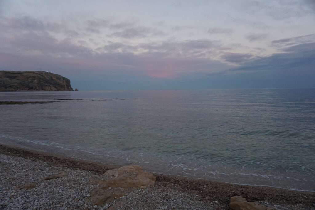 Rocky beach in Spain with pink and purple sunset over the Mediterranean