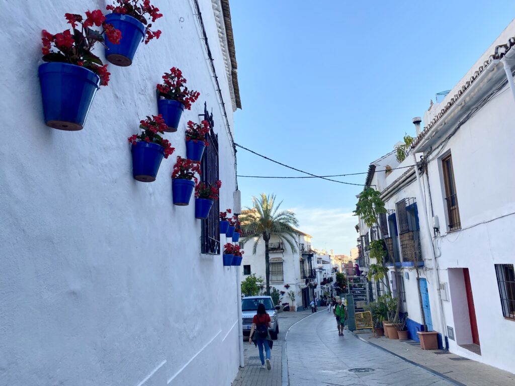 White buildings with flower pots hanging on them along a narrow street in Old Town Marbella Spain
