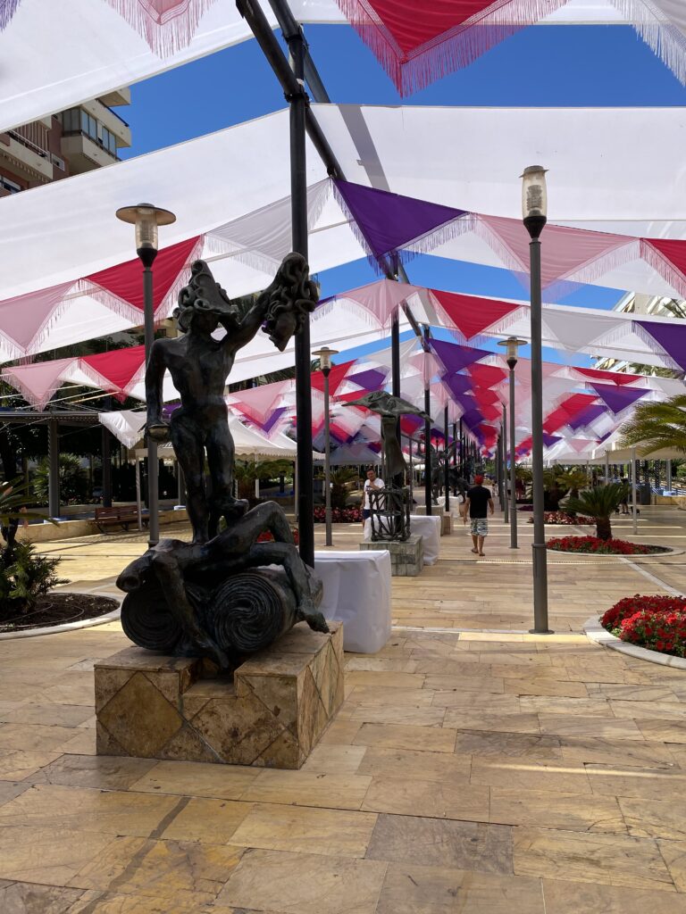 Walkway with Salvador Dali statues in the center and colorful fabric coverings overhead