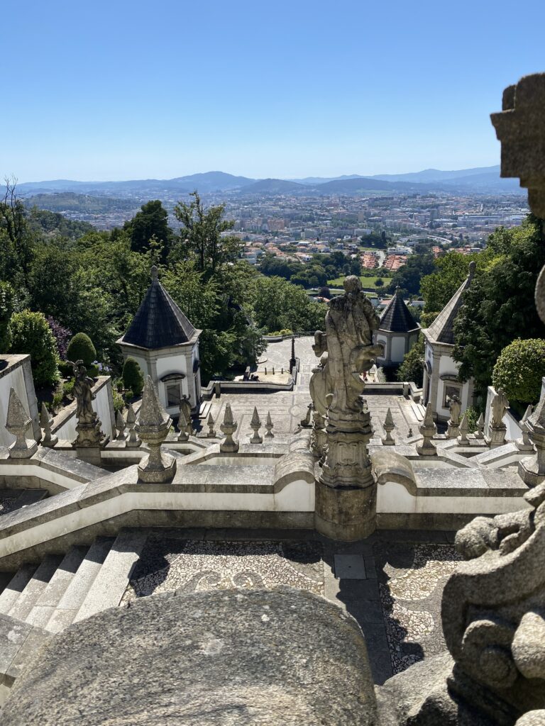 View of town below from a stone staircase with sculptures and fountains