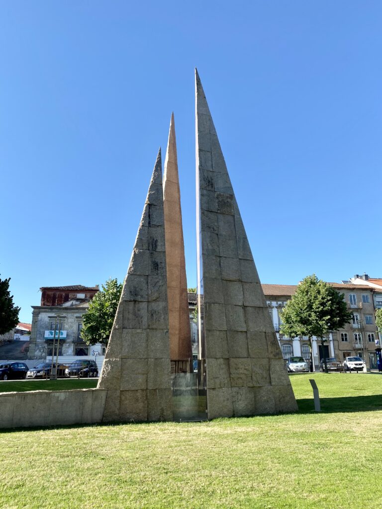 Tall triangular sculpture in a grassy space
