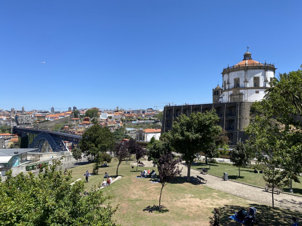 View from a park of a circular monastery on top of a hill, a bridge, and cityscape