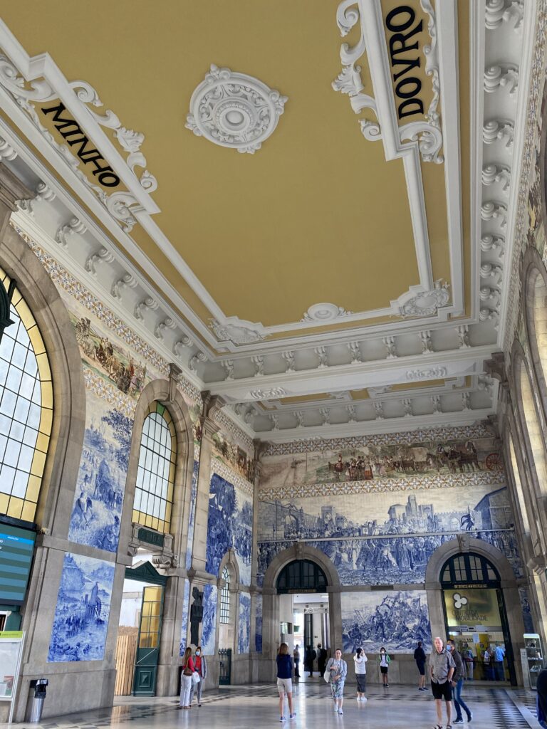 Train station lobby with detailed tile murals on the wall and ornate ceiling