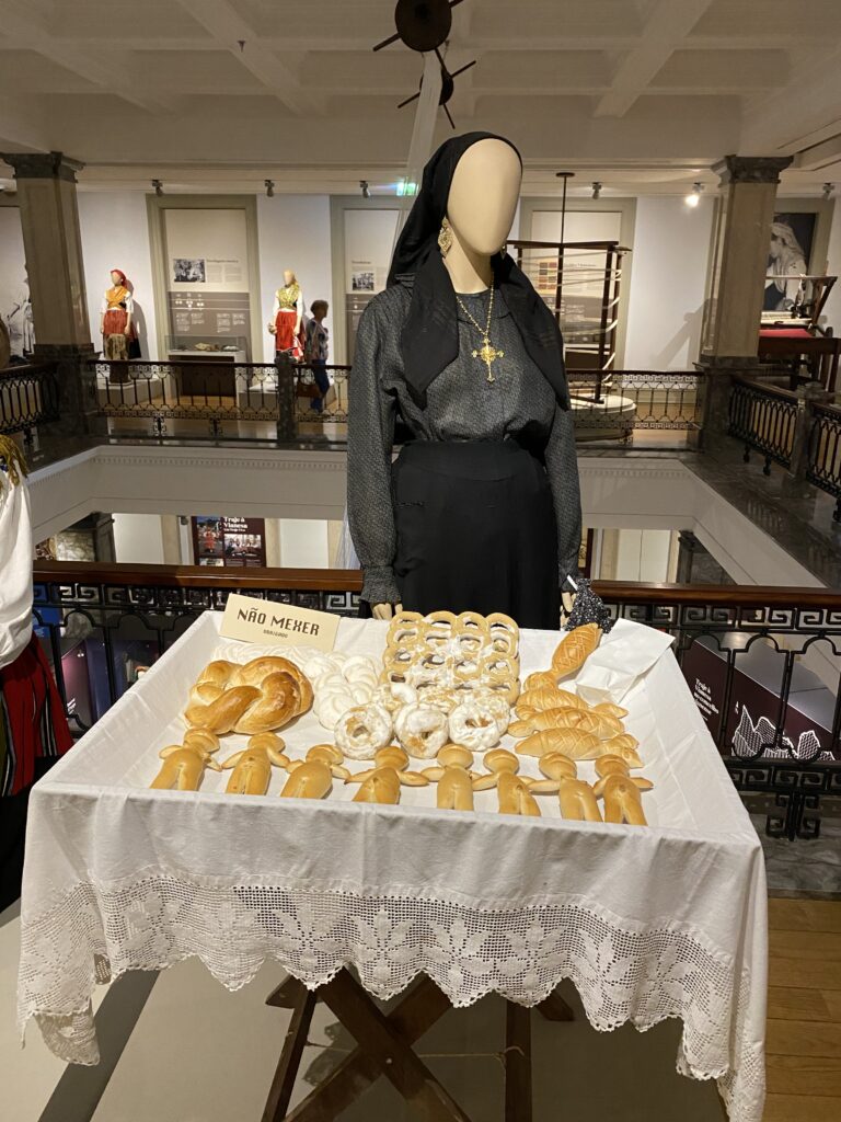 Museum mannequin wearing traditional northern Portuguese women's clothing with a pastry cart in front of it
