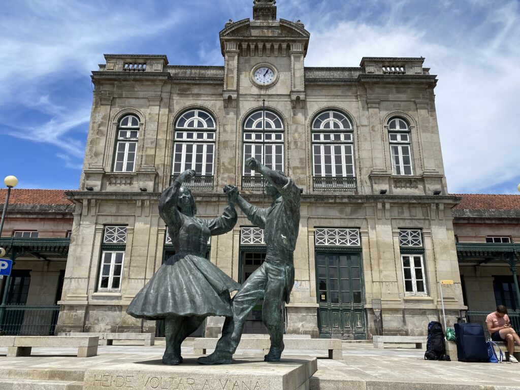 Statue of a man and woman dancing in front of a Portugal train station
