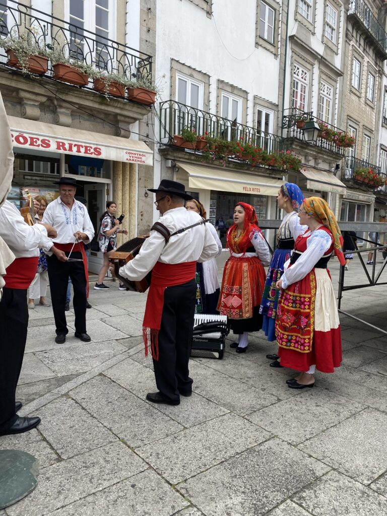 People in historic town center dressed in traditional Portuguese clothing singing and playing instruments