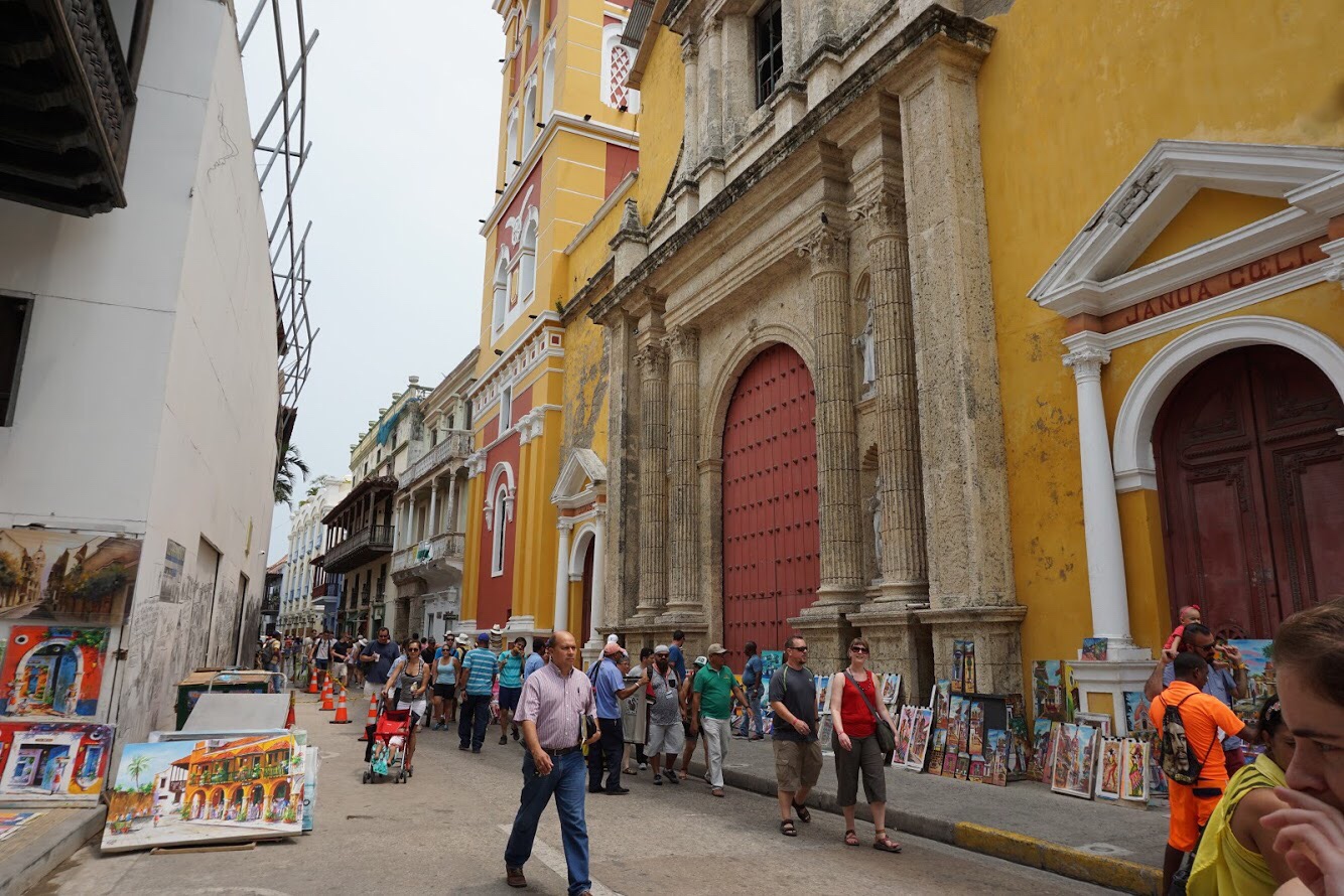 Street with art vendors on sidewalks and a yellow historic church