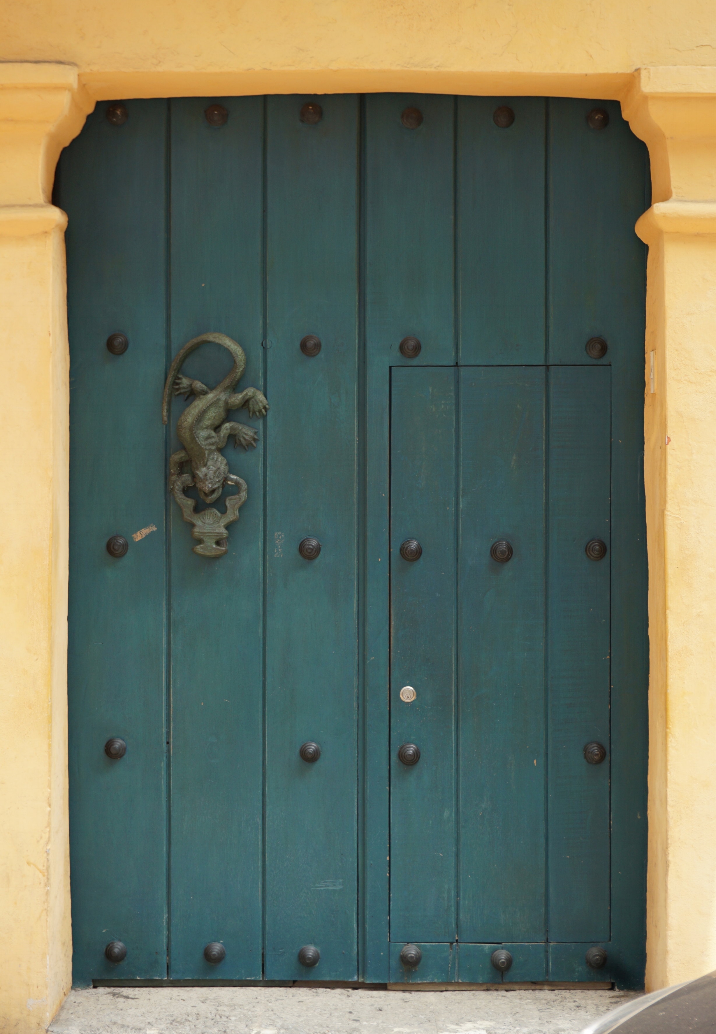 Spanish-style teal double door with a decorative door knocker