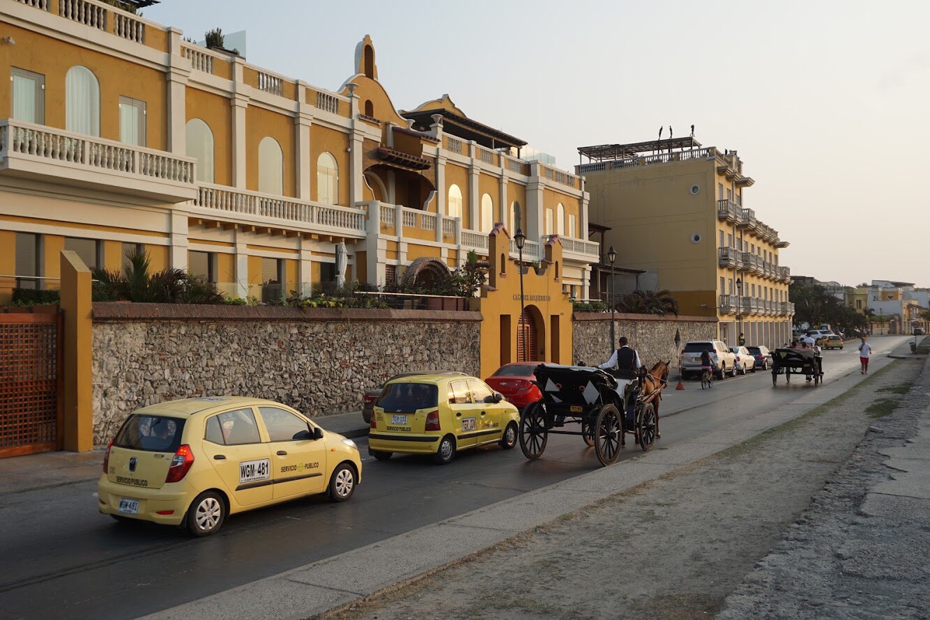 Yellow Spanish-style buildings opposite a road with taxis and a horse-drawn carriage