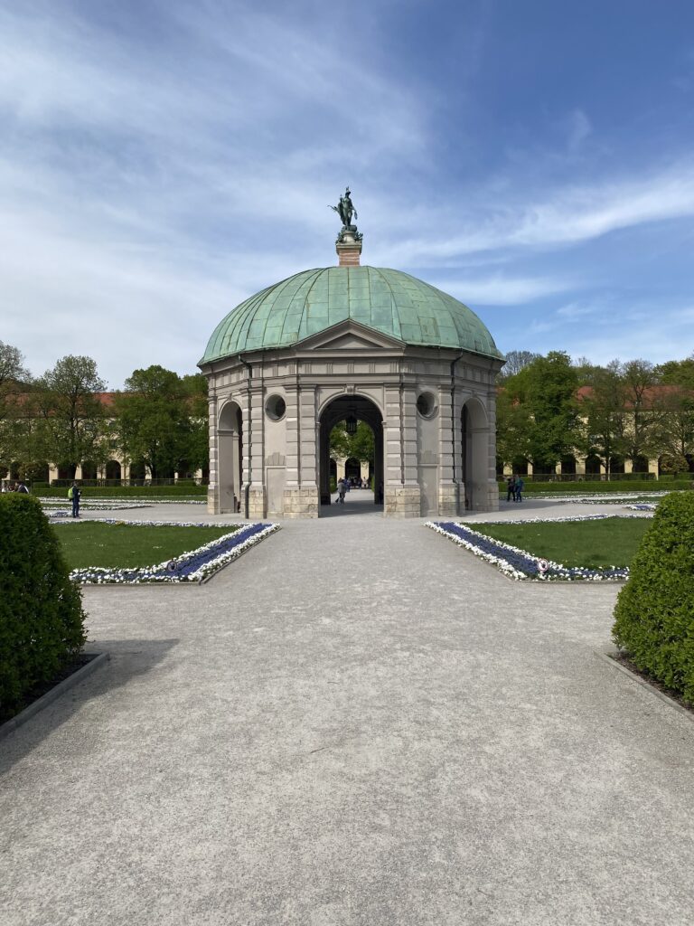 Round stone pavilion in the center of gravel paths and manicured gardens in Munich