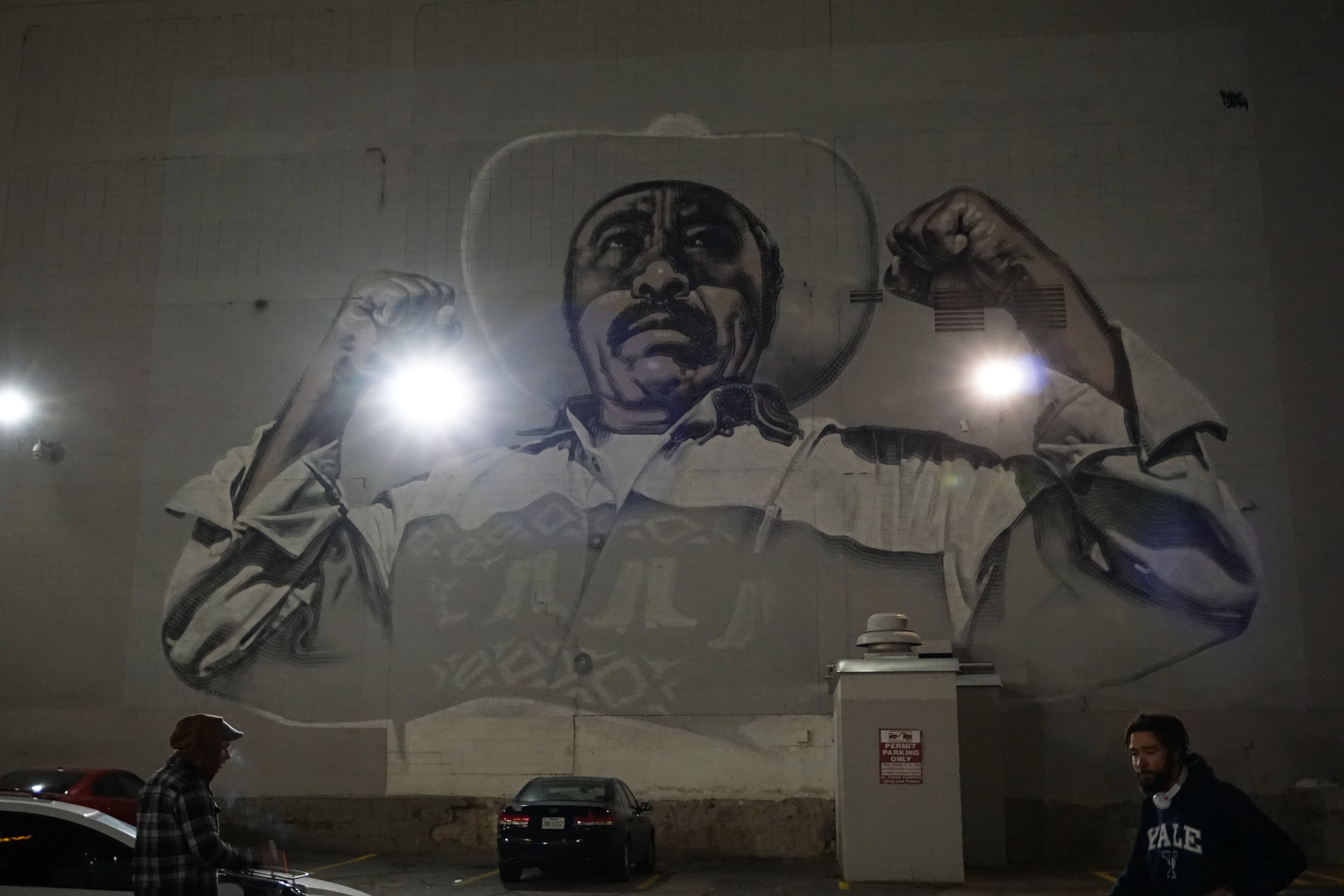 Street art mural of a Mexican man with his arms up and hands in fists