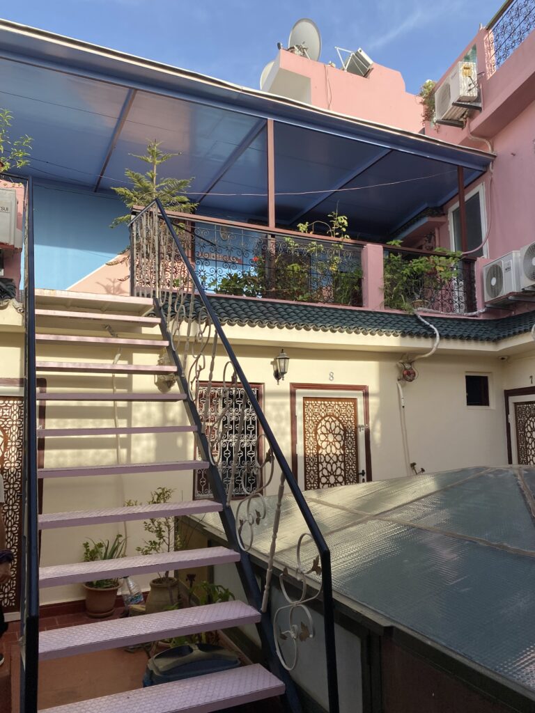 Rooftop courtyard of Moroccan homestay with pink walls and staircase