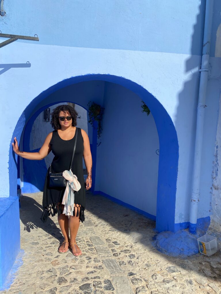 Woman standing in archway painted light blue in Chefchaouen Morocco