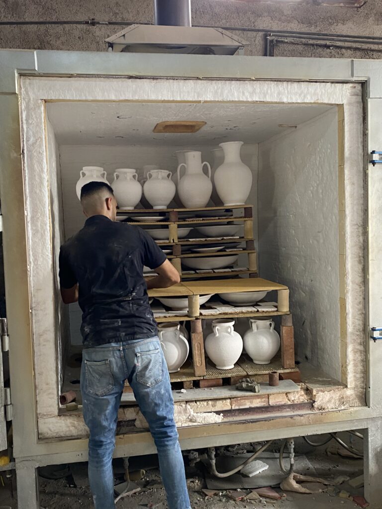 Man arranging unpainted clay pots in a storage box